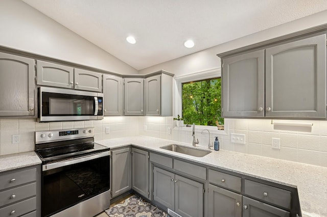 5101 201st St N, Forest Lake, MN 55025 - kitchen featuring appliances with stainless steel finishes, a sink, gray cabinetry, vaulted ceiling, and decorative backsplash