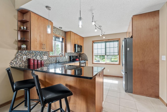 7734 Lancaster Ave NE, Otsego, MN 55301 - kitchen with appliances with stainless steel finishes, a peninsula, dark countertops, tasteful backsplash, and brown cabinets