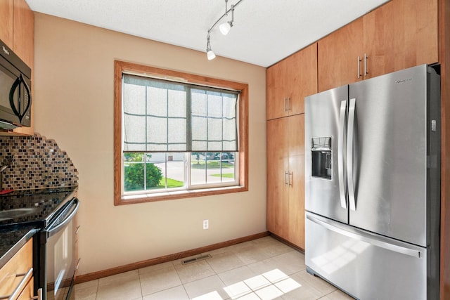 7734 Lancaster Ave NE, Otsego, MN 55301 - kitchen featuring stainless steel appliances, decorative backsplash, dark countertops, track lighting, and light tile patterned floors