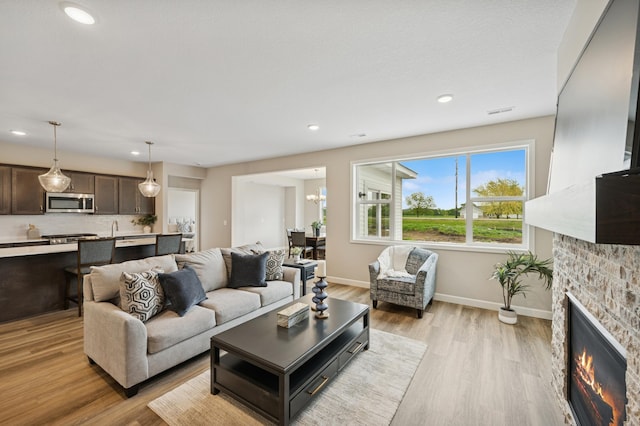 464 Whitewater Ct, Delano, MN 55328 - living room with a stone fireplace, baseboards, light wood-type flooring, recessed lighting, and a chandelier