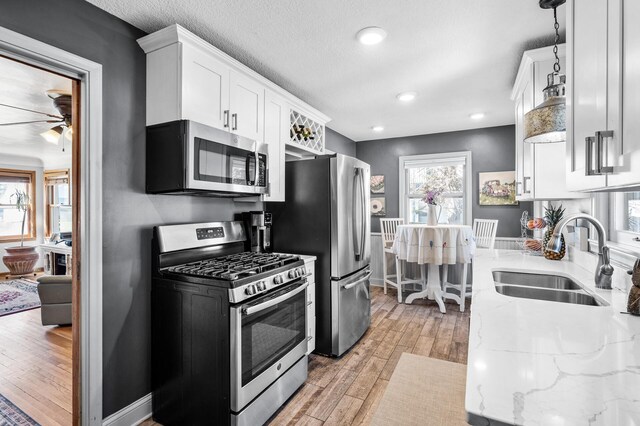 1551 Margaret St, Saint Paul, MN 55106 - kitchen featuring appliances with stainless steel finishes, a sink, white cabinetry, light wood-type flooring, and plenty of natural light