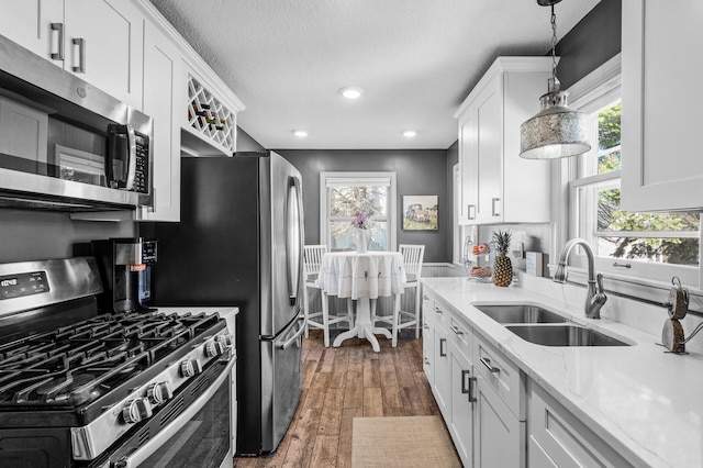 1551 Margaret St, Saint Paul, MN 55106 - kitchen with appliances with stainless steel finishes, a sink, white cabinetry, dark wood finished floors, and pendant lighting