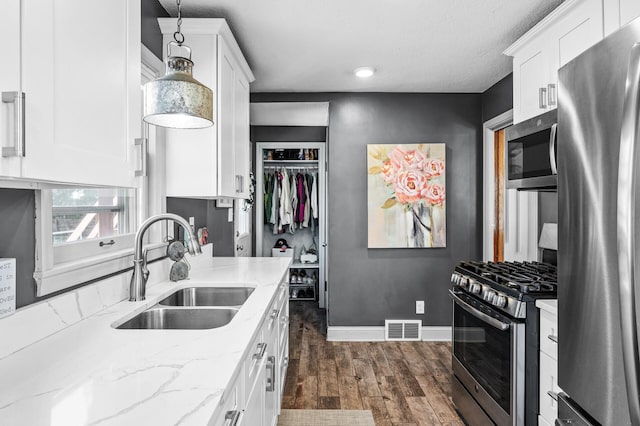 1551 Margaret St, Saint Paul, MN 55106 - kitchen with appliances with stainless steel finishes, a sink, white cabinets, and dark wood-style floors