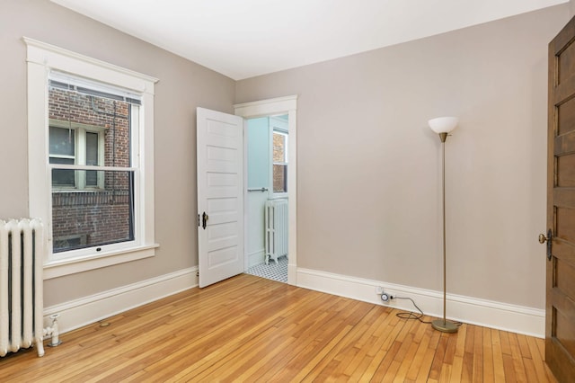 2227 Garfield Ave, Minneapolis, MN 55405 - unfurnished room featuring radiator heating unit, light wood-style floors, and baseboards