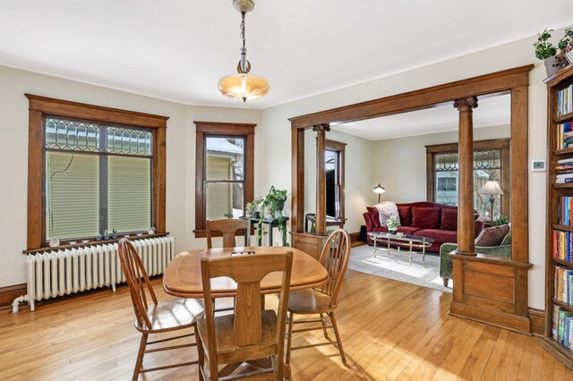 2227 Garfield Ave, Minneapolis, MN 55405 - dining room featuring radiator, light wood-style floors, baseboards, and ornate columns