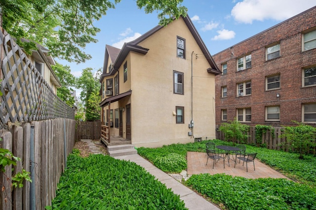 2227 Garfield Ave, Minneapolis, MN 55405 - rear view of property featuring stucco siding, a fenced backyard, and a patio