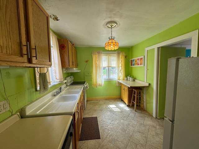 205 Lake Park Blvd, Fairmont, MN 56031 - kitchen featuring freestanding refrigerator, range with electric cooktop, brown cabinetry, and baseboards
