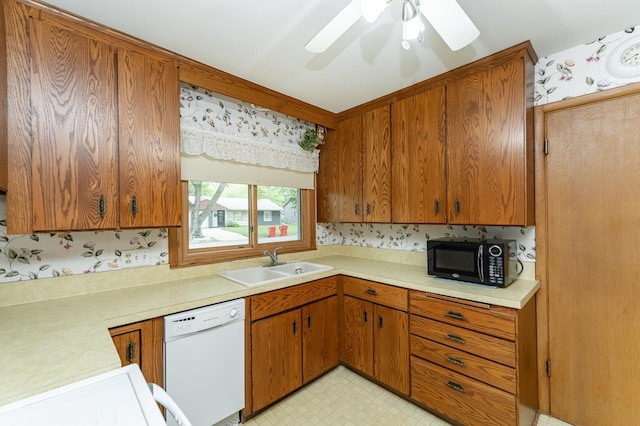 kitchen featuring a sink, black microwave, white dishwasher, light countertops, and brown cabinetry