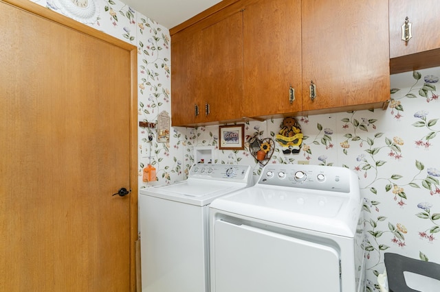 laundry room featuring wallpapered walls, washing machine and clothes dryer, and cabinet space