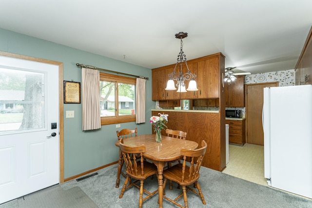dining room with a ceiling fan, baseboards, and light carpet