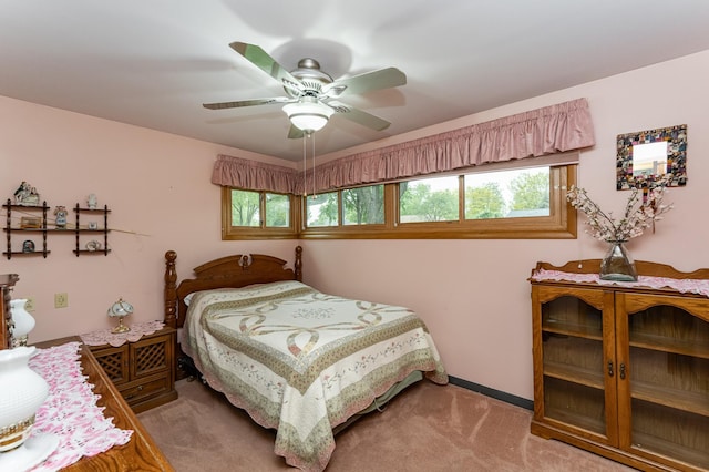 bedroom featuring multiple windows, light carpet, and a ceiling fan
