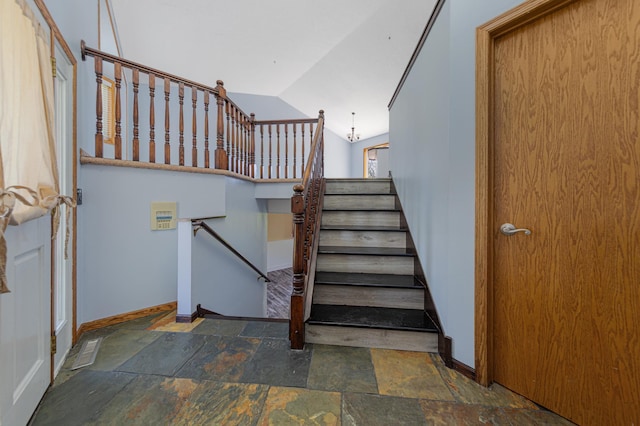 stairway with stone finish floors, baseboards, and vaulted ceiling