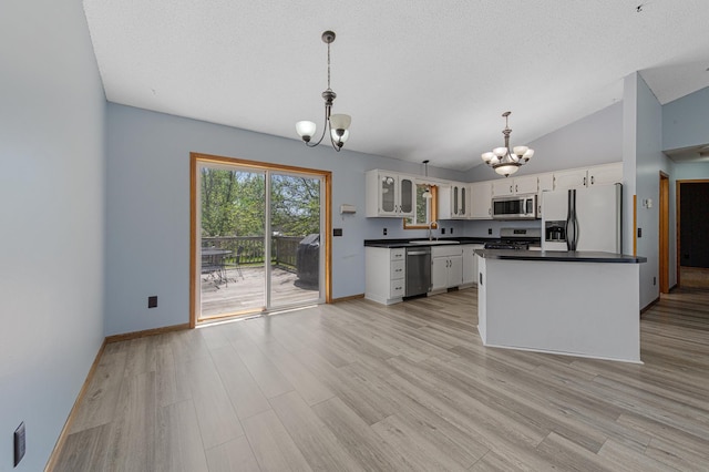 kitchen with stainless steel appliances, a chandelier, a sink, dark countertops, and white cabinets