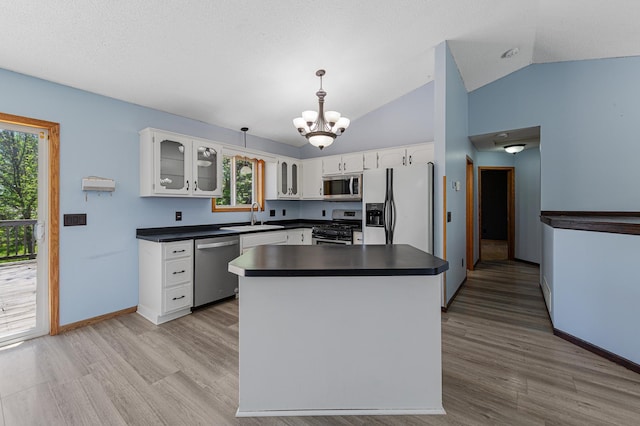 kitchen with stainless steel appliances, dark countertops, a chandelier, glass insert cabinets, and white cabinets