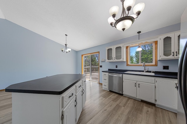 kitchen with appliances with stainless steel finishes, a sink, dark countertops, a chandelier, and lofted ceiling
