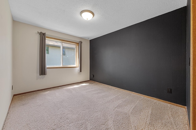 spare room with carpet floors, a textured ceiling, and baseboards