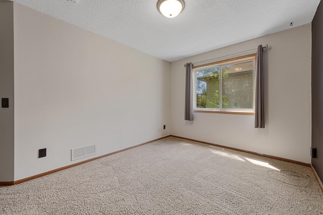 carpeted empty room with a textured ceiling and baseboards
