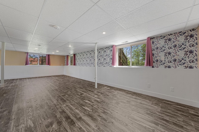 basement featuring wood finished floors, baseboards, and a paneled ceiling