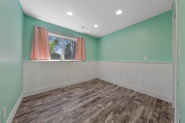 empty room featuring wood finished floors, a wainscoted wall, recessed lighting, and baseboards