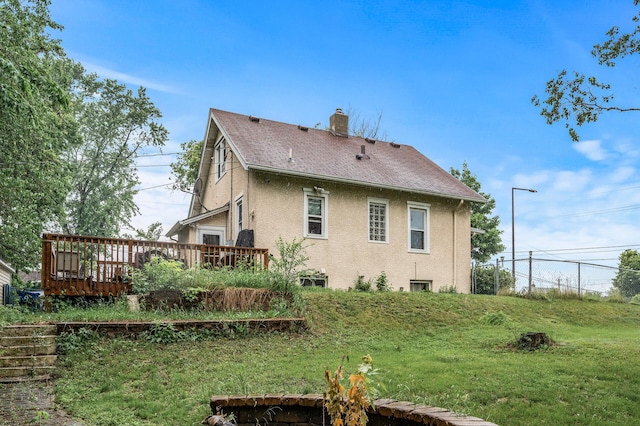 48 Jessamine Ave E, Saint Paul, MN 55117 - back of property featuring stucco siding, a chimney, a deck, a shingled roof, and a lawn
