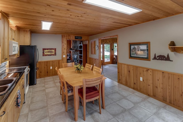 dining room featuring a wainscoted wall, wooden walls, wooden ceiling, and light tile patterned floors