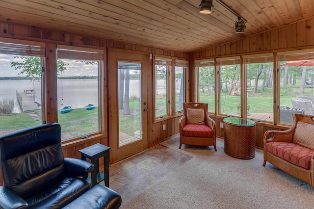 sunroom / solarium with vaulted ceiling, wooden ceiling, wooden walls, a water view, and baseboards