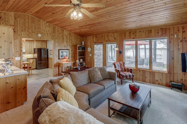 living area with vaulted ceiling, wood walls, wooden ceiling, a ceiling fan, and light carpet