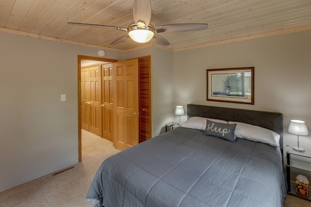 bedroom with wood ceiling, carpet flooring, a closet, a ceiling fan, and crown molding