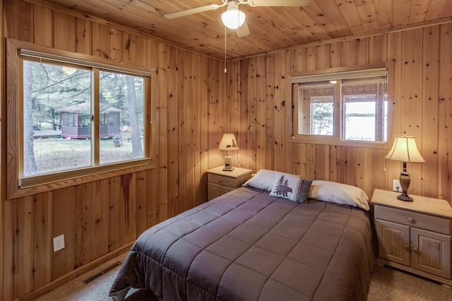 bedroom featuring wood walls, wood ceiling, light carpet, and ceiling fan