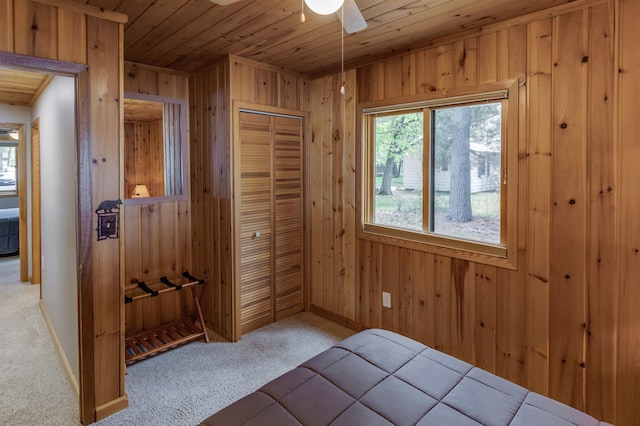 unfurnished bedroom with wood ceiling, carpet, wood walls, a closet, and baseboards