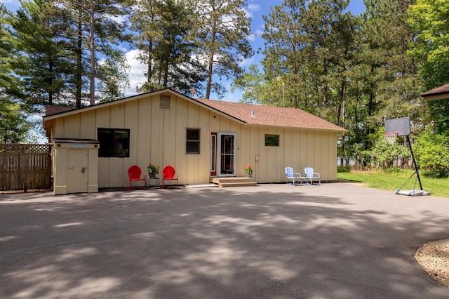 rear view of property featuring board and batten siding, roof with shingles, and a patio area