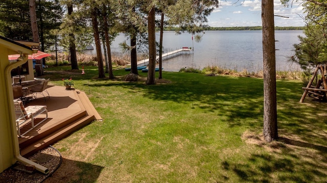 view of grassy yard with a dock and a deck with water view