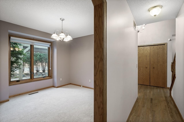 2970 Western Ave N, Roseville, MN 55113 - hall with a chandelier, a textured ceiling, baseboards, and wood finished floors