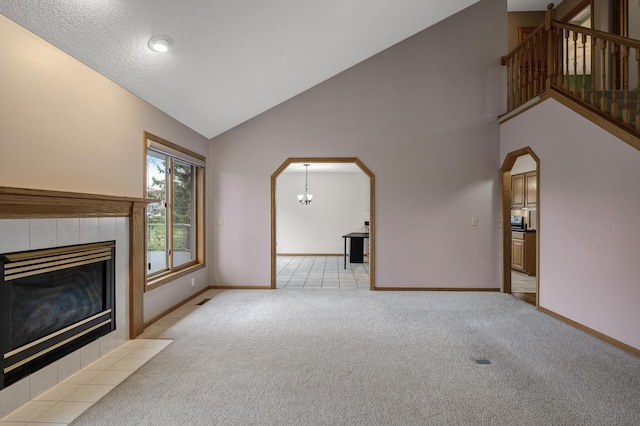2970 Western Ave N, Roseville, MN 55113 - unfurnished living room featuring light carpet, baseboards, a tile fireplace, stairs, and high vaulted ceiling