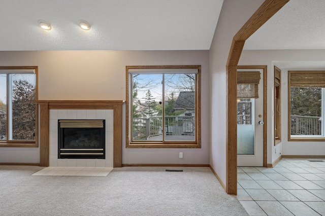 2970 Western Ave N, Roseville, MN 55113 - unfurnished living room with baseboards, light carpet, a tiled fireplace, and a textured ceiling