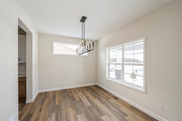 869 Greywood Blvd SW, Delano, MN 55328 - unfurnished dining area with light wood-style floors, healthy amount of natural light, a chandelier, and baseboards