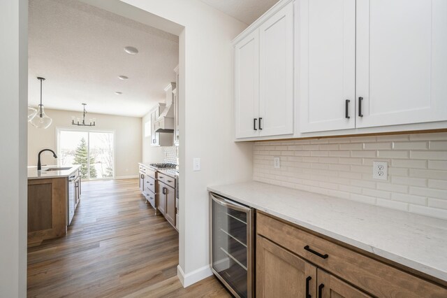869 Greywood Blvd SW, Delano, MN 55328 - kitchen with beverage cooler, a sink, light wood-style floors, tasteful backsplash, and white cabinets