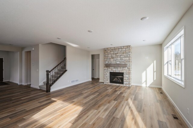 869 Greywood Blvd SW, Delano, MN 55328 - unfurnished living room featuring wood finished floors, stairs, a fireplace, and baseboards