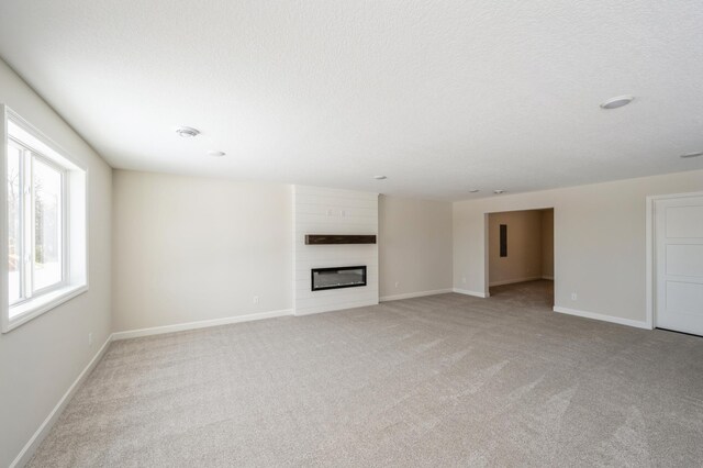 869 Greywood Blvd SW, Delano, MN 55328 - unfurnished living room with light colored carpet, a large fireplace, baseboards, and a textured ceiling