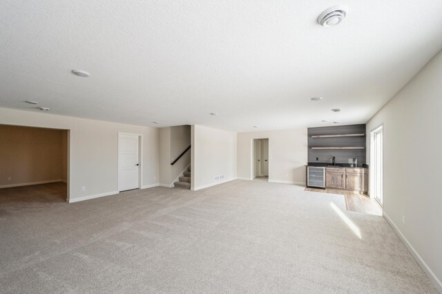 869 Greywood Blvd SW, Delano, MN 55328 - unfurnished living room with bar with sink, stairway, light colored carpet, and baseboards