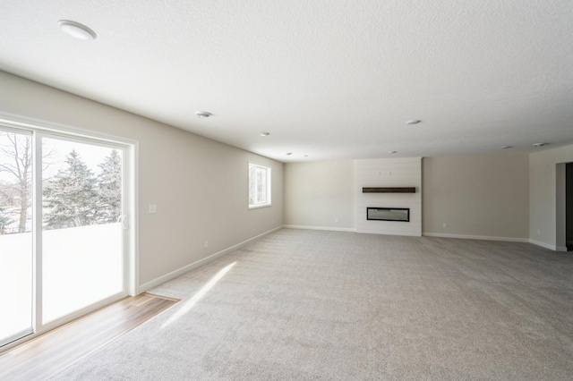 869 Greywood Blvd SW, Delano, MN 55328 - unfurnished living room with light carpet, a fireplace, baseboards, and a textured ceiling