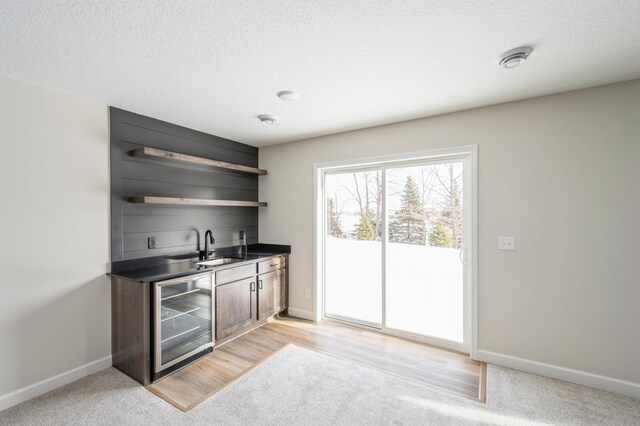869 Greywood Blvd SW, Delano, MN 55328 - indoor wet bar with wine cooler, baseboards, a textured ceiling, and light carpet