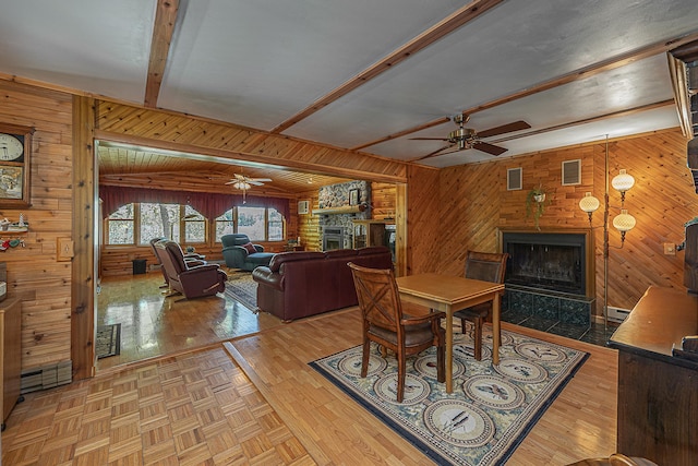224 Norman Point Rd NW, Longville, MN 56655 - dining space with a large fireplace, a ceiling fan, wooden walls, beamed ceiling, and parquet floors