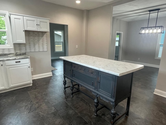 309 4th St, Marshall, MN 56258 - kitchen featuring white cabinetry, baseboards, light countertops, hanging light fixtures, and a kitchen island