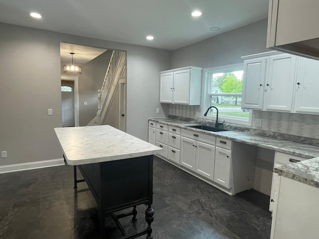 309 4th St, Marshall, MN 56258 - kitchen featuring a sink, decorative backsplash, white cabinets, recessed lighting, and baseboards