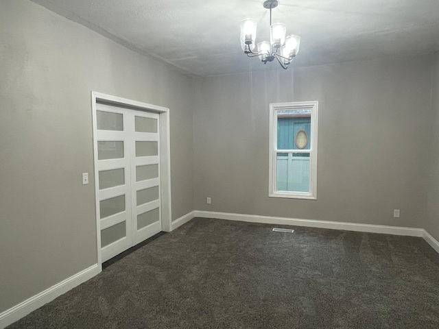 309 4th St, Marshall, MN 56258 - empty room featuring a chandelier, dark colored carpet, and baseboards