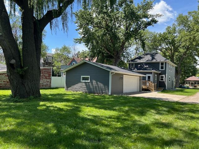309 4th St, Marshall, MN 56258 - view of side of home featuring an outdoor structure, concrete driveway, and a yard