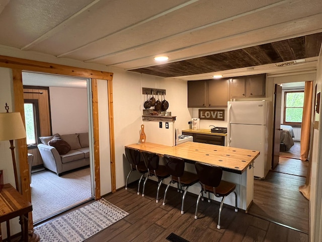 11216 State Highway 27, Beaver Twp, MN 55783 - kitchen with wooden counters, freestanding refrigerator, a peninsula, dark wood-style flooring, and a kitchen bar