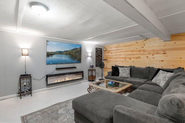 750 Prairie Ave SE, Cokato, MN 55321 - living room featuring finished concrete flooring, wood walls, a glass covered fireplace, baseboards, and beam ceiling