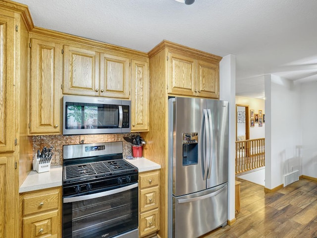 7349 Drew Ave N, Brooklyn Park, MN 55443 - kitchen featuring stainless steel appliances, wood finished floors, light countertops, backsplash, and baseboards